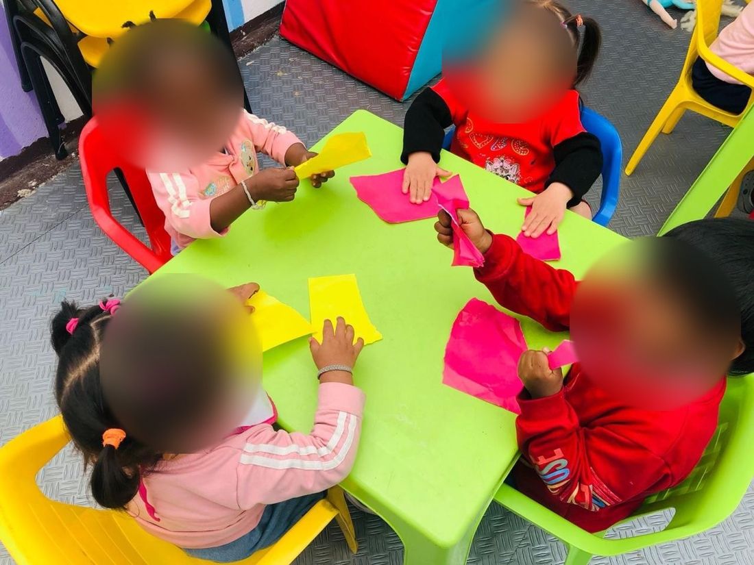 Niños de primera infancia rasgando papel de colores en una mesa